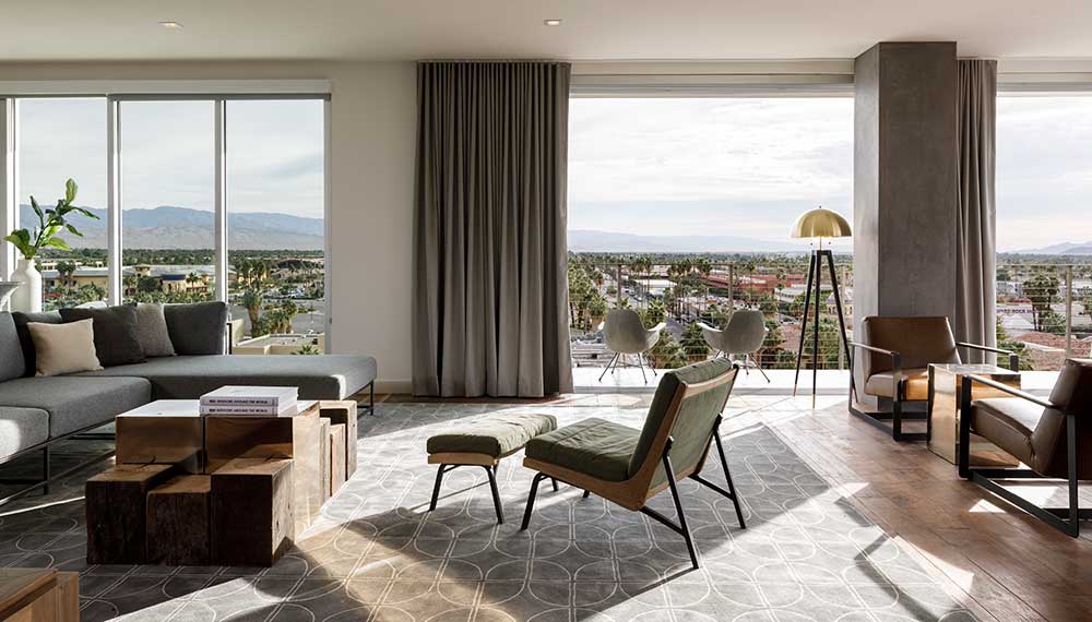 Hotel suite with floor-to-ceiling windows overlooking Palm Springs and surrounding mountains